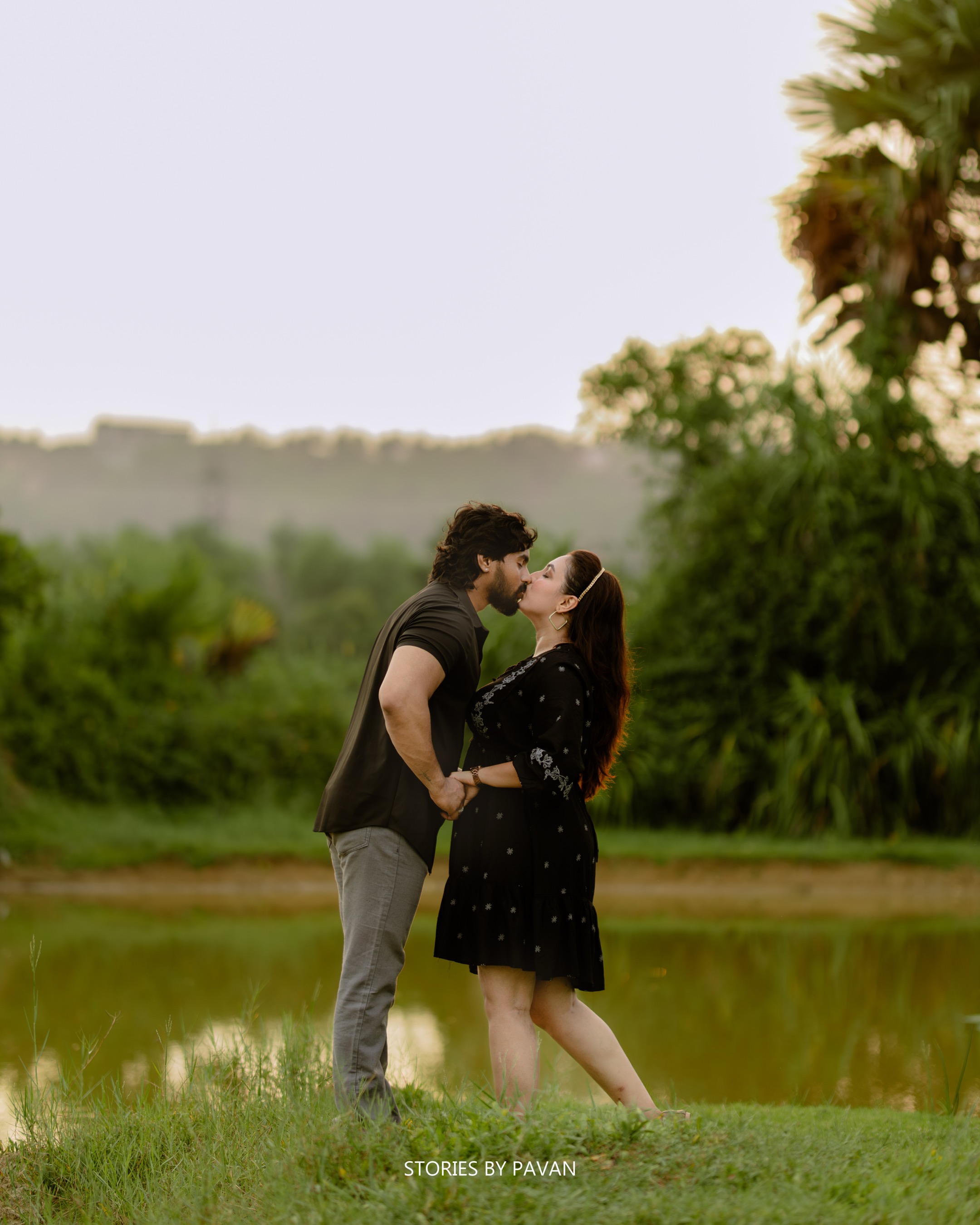 Couple sharing a kiss by a pond at golden hour
