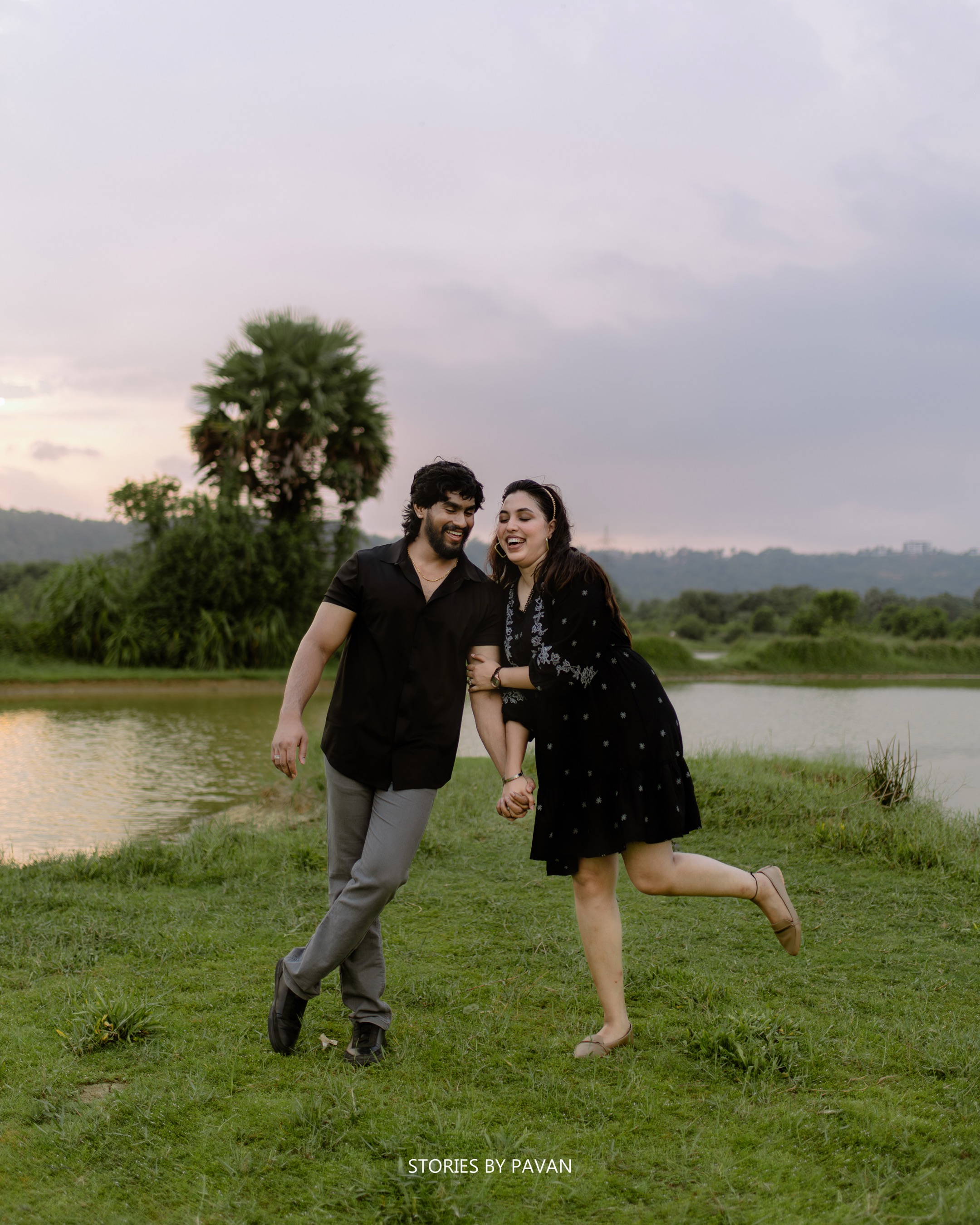 Couple laughing and running together beside a lake at dusk