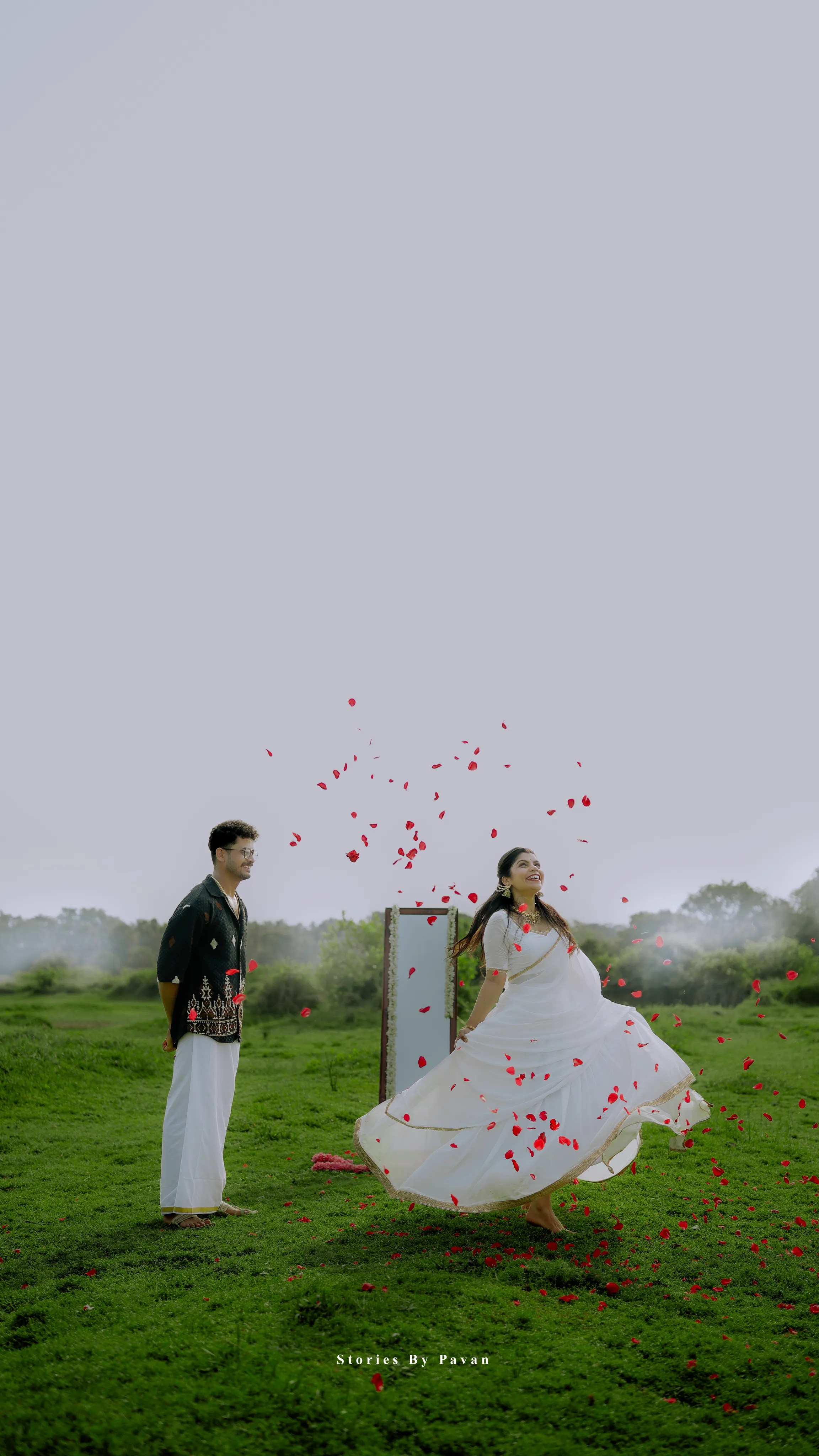 Bride twirling in a white dress as rose petals fall around her in a green field