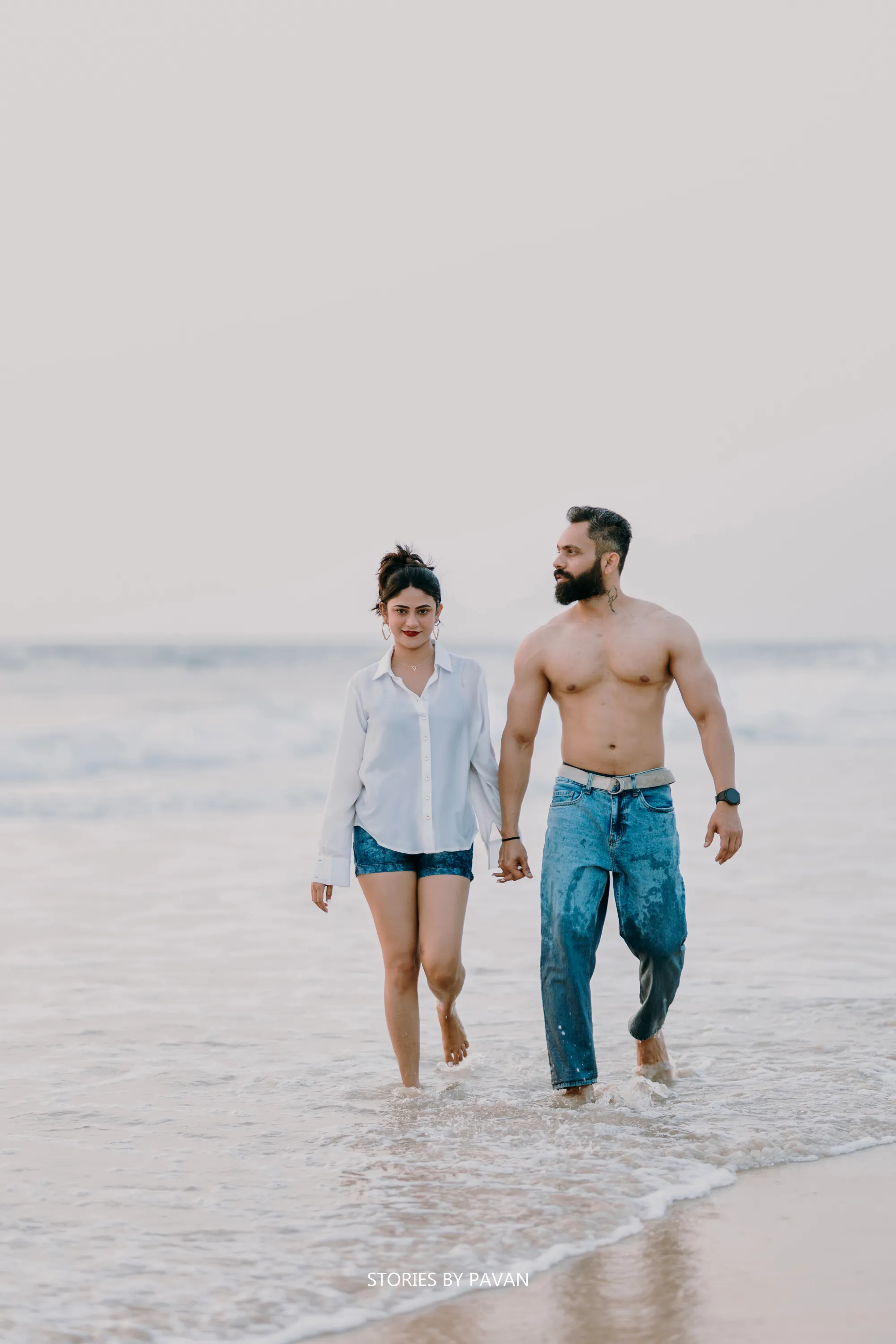 Couple walking hand in hand through the shallow surf on a beach